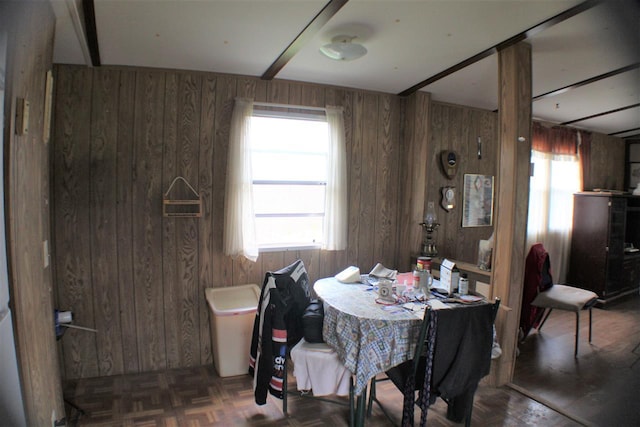 dining area with dark parquet floors, wood walls, and a healthy amount of sunlight