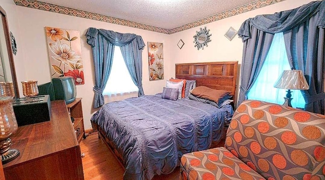 bedroom with a textured ceiling and dark wood-type flooring