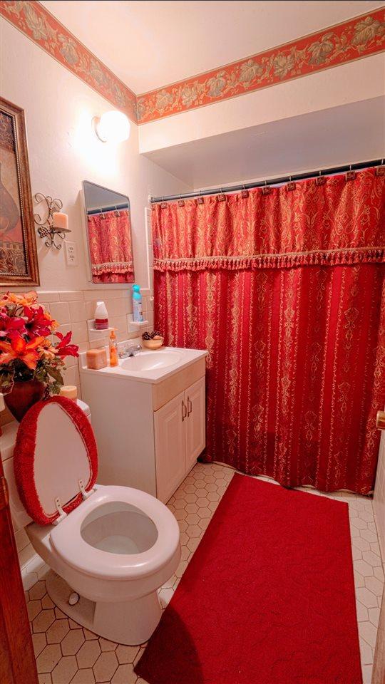 bathroom with backsplash, toilet, tile floors, and vanity with extensive cabinet space