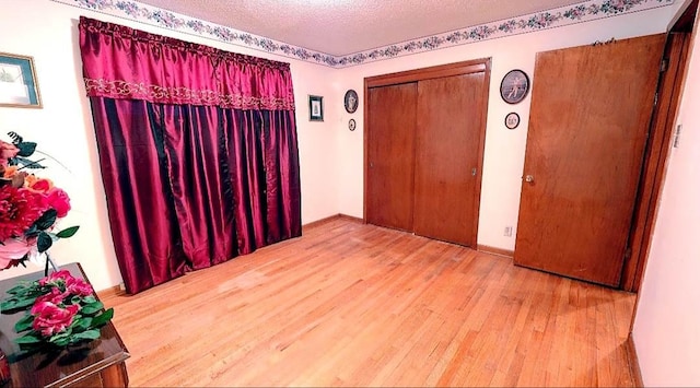 spare room featuring light hardwood / wood-style floors and a textured ceiling