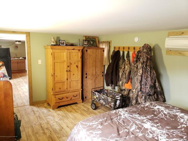 bedroom featuring an AC wall unit, black fridge, sink, and light wood-type flooring