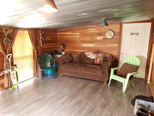 living room with lofted ceiling, dark wood-type flooring, and wooden walls