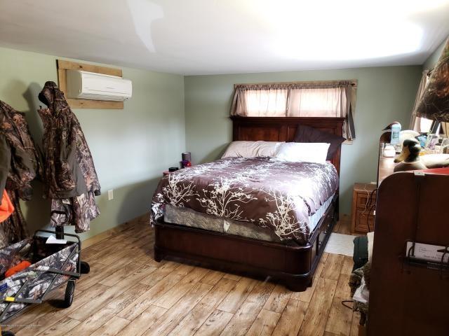 bedroom featuring a wall mounted AC and light hardwood / wood-style floors