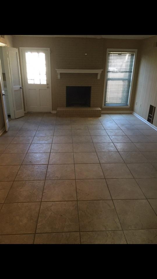 unfurnished living room with light tile flooring and a fireplace