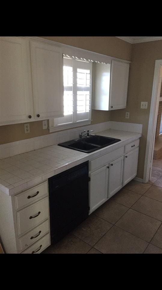 kitchen with tile counters, sink, dark tile flooring, white cabinets, and dishwasher