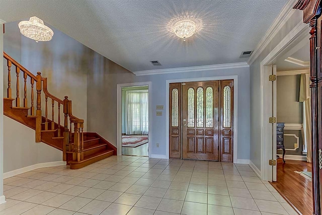 tiled foyer featuring an inviting chandelier, a textured ceiling, and crown molding