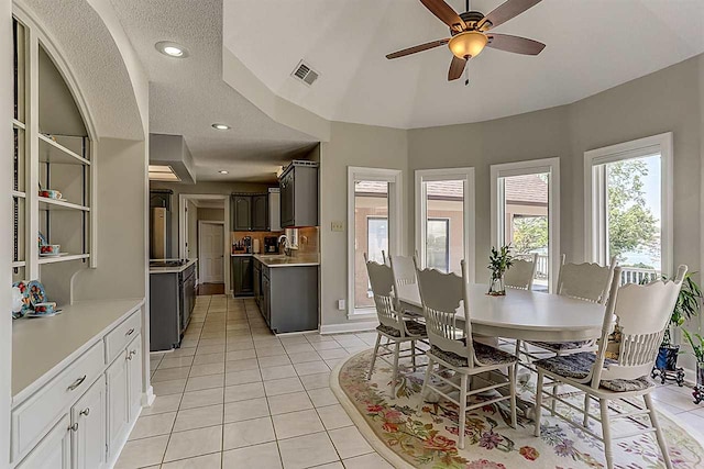 dining room featuring lofted ceiling, a textured ceiling, ceiling fan, and light tile flooring