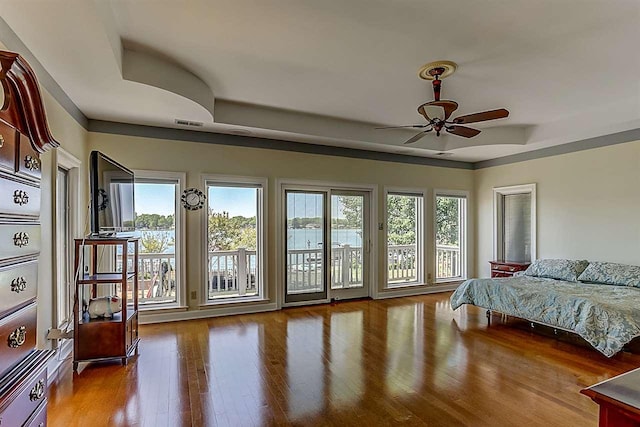 bedroom featuring ceiling fan, access to exterior, a raised ceiling, and dark hardwood / wood-style floors