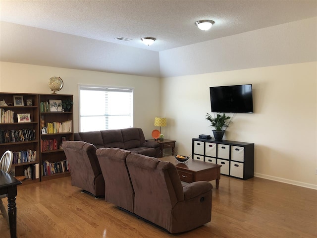 living room with lofted ceiling, a textured ceiling, and wood-type flooring