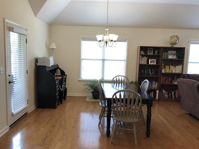 dining area featuring light hardwood / wood-style floors, a notable chandelier, lofted ceiling, and a wealth of natural light