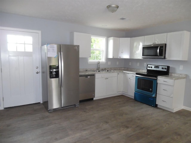 kitchen with stainless steel appliances, light stone countertops, white cabinetry, dark hardwood / wood-style floors, and sink