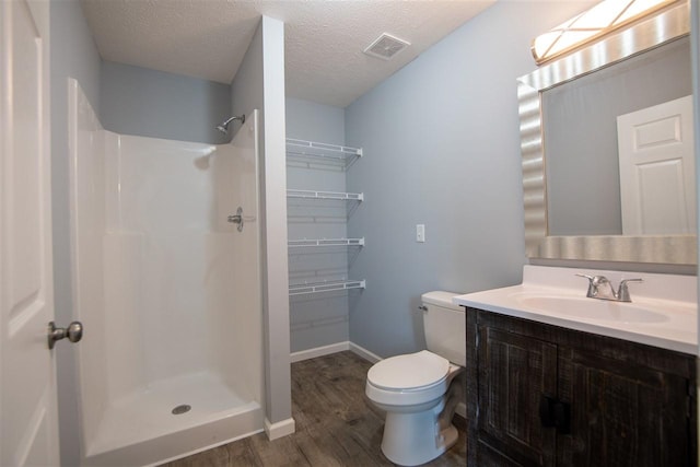 bathroom featuring toilet, a shower, hardwood / wood-style flooring, vanity, and a textured ceiling