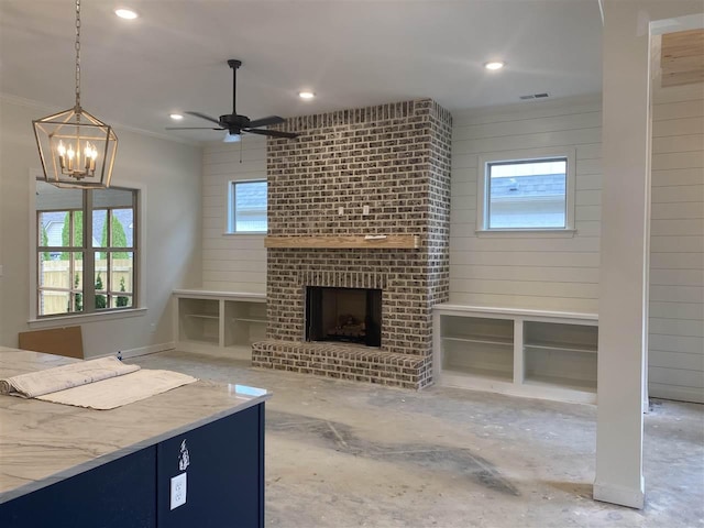 unfurnished living room featuring ceiling fan with notable chandelier and a brick fireplace