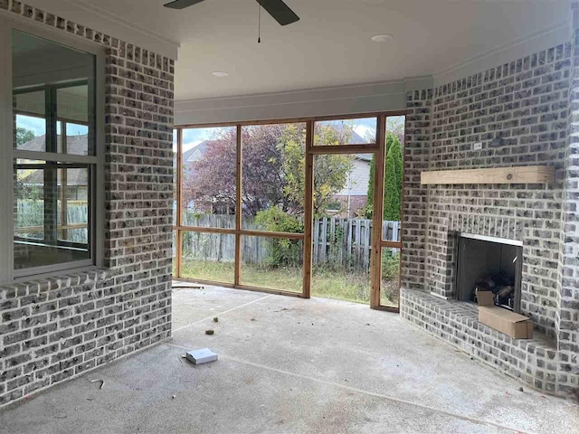 unfurnished sunroom with ceiling fan, an outdoor brick fireplace, and a healthy amount of sunlight