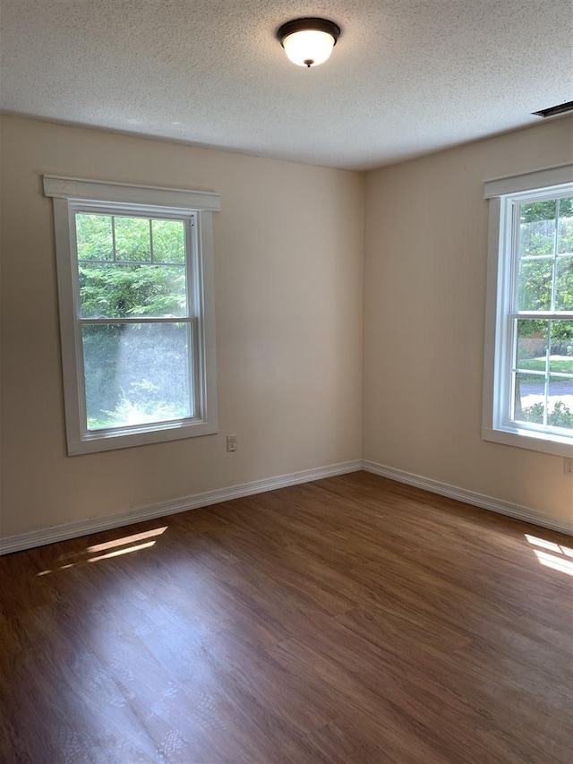 spare room featuring a textured ceiling and dark hardwood / wood-style floors