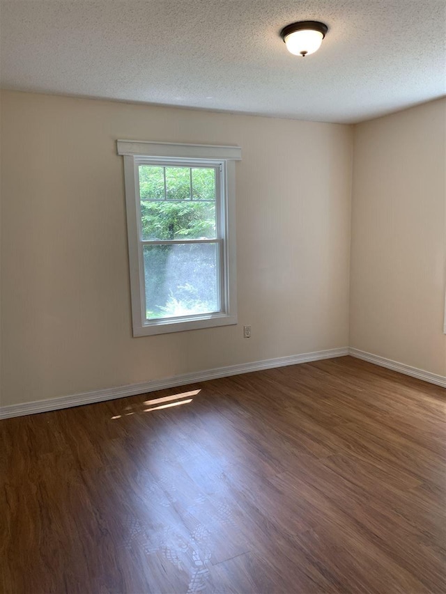 spare room with a textured ceiling and dark wood-type flooring