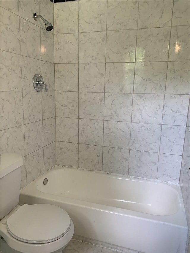 bathroom with toilet and tiled shower / bath