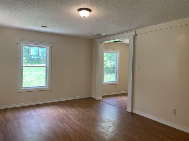 empty room with a textured ceiling and dark wood-type flooring