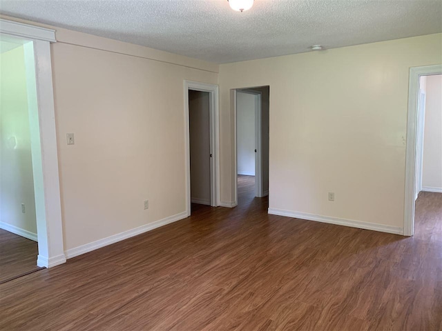 unfurnished room with a textured ceiling and dark hardwood / wood-style floors