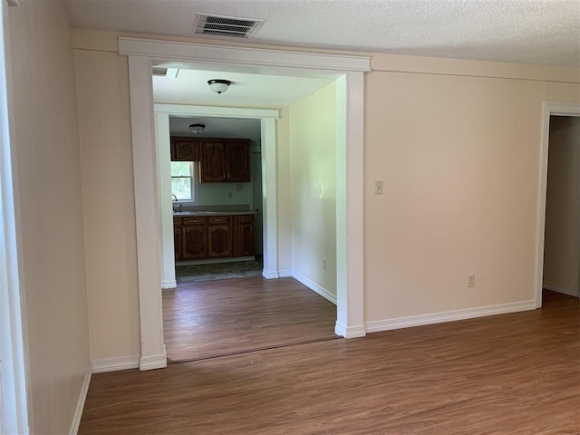 hall with dark hardwood / wood-style flooring, a textured ceiling, and sink