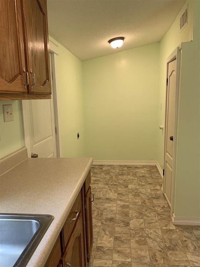 kitchen featuring light tile flooring, a textured ceiling, and sink