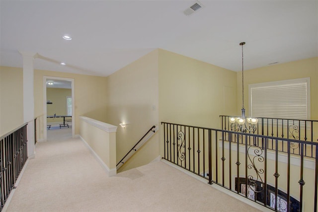 corridor with light colored carpet and a chandelier