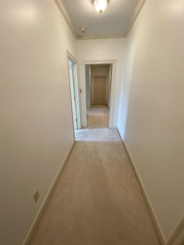 corridor featuring ornamental molding and light colored carpet