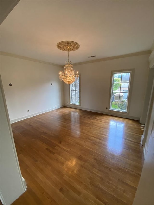 unfurnished room featuring crown molding, dark hardwood / wood-style floors, and an inviting chandelier