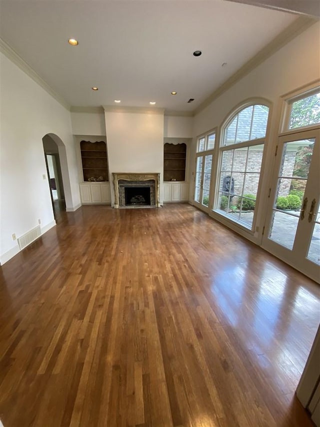 unfurnished living room with a towering ceiling, ornamental molding, dark hardwood / wood-style floors, and french doors