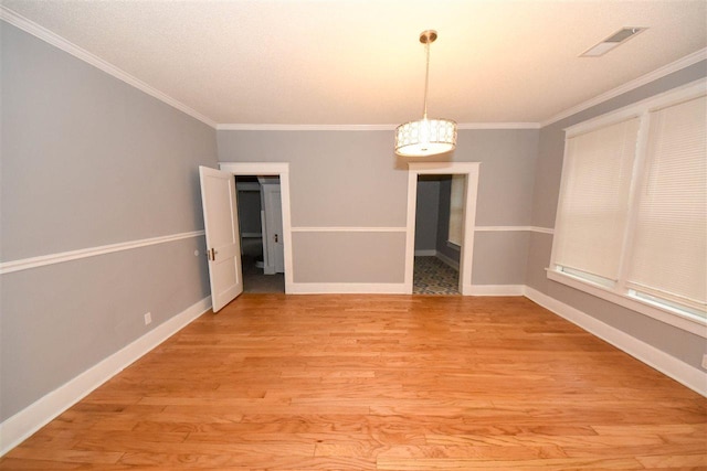 spare room featuring a chandelier, light hardwood / wood-style flooring, and crown molding