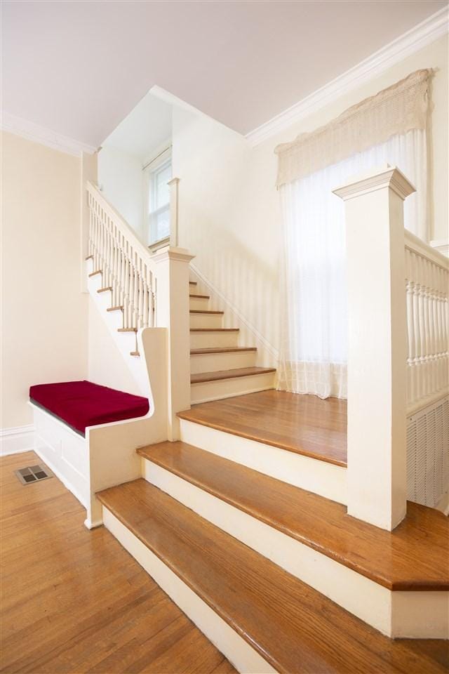 staircase with ornamental molding and wood-type flooring