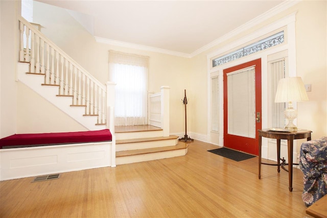 foyer entrance with light hardwood / wood-style floors and ornamental molding