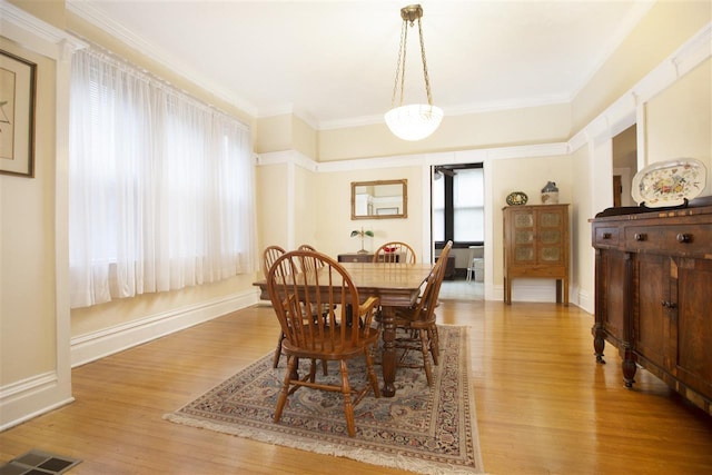 dining area with light hardwood / wood-style flooring and crown molding