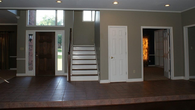 foyer entrance with dark tile floors and ornamental molding