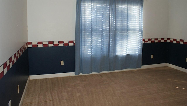 empty room featuring dark colored carpet and a healthy amount of sunlight