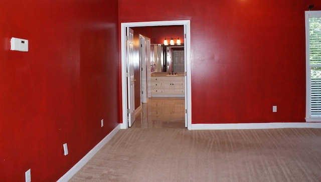 hall with sink and light colored carpet