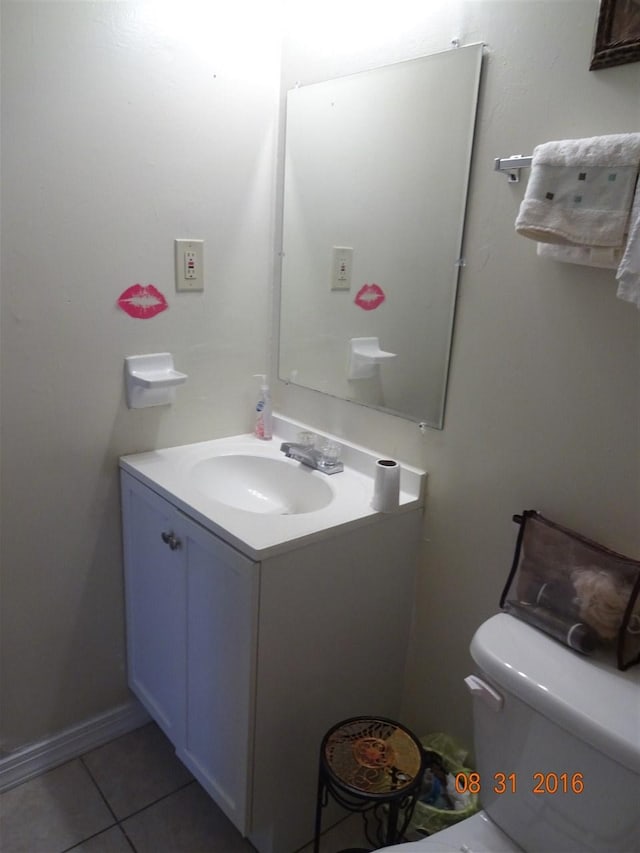 bathroom with toilet, vanity, and tile flooring