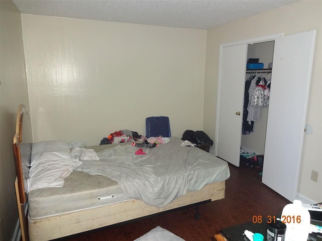 bedroom featuring a textured ceiling, dark hardwood / wood-style floors, and a closet