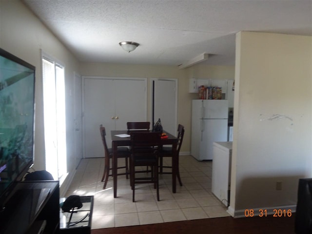 dining space featuring a textured ceiling, a healthy amount of sunlight, and light tile floors