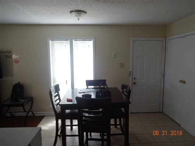 tiled dining space with a textured ceiling