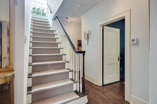 stairway featuring crown molding and dark hardwood / wood-style flooring