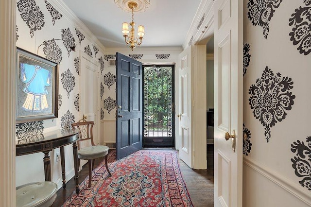 foyer entrance featuring a notable chandelier, dark hardwood / wood-style floors, and ornamental molding