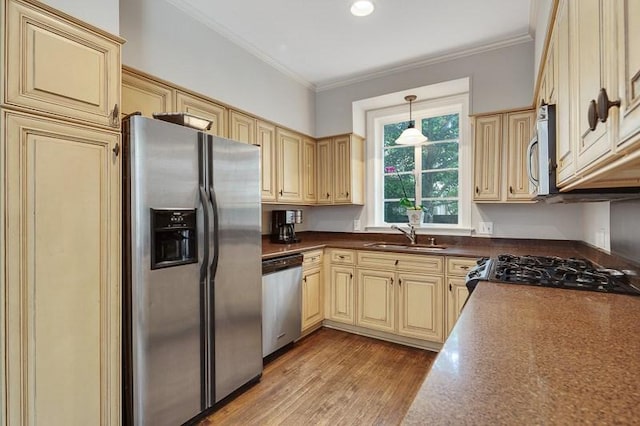 kitchen with appliances with stainless steel finishes, pendant lighting, dark wood-type flooring, sink, and crown molding