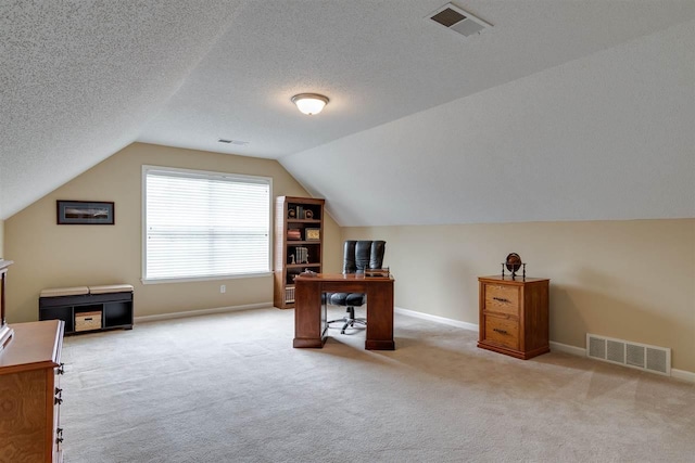 carpeted office space featuring a textured ceiling and vaulted ceiling