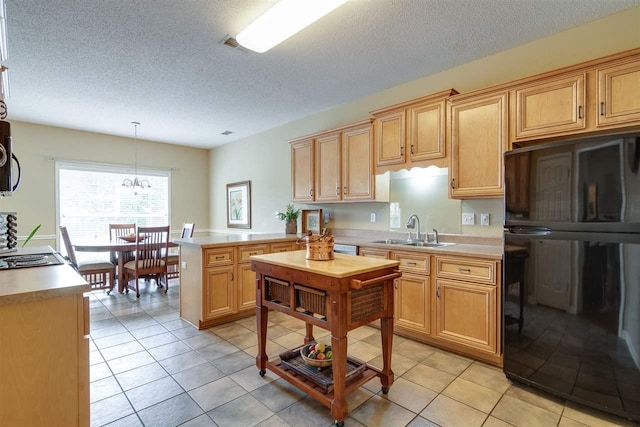 kitchen featuring an inviting chandelier, sink, light tile floors, black fridge, and pendant lighting