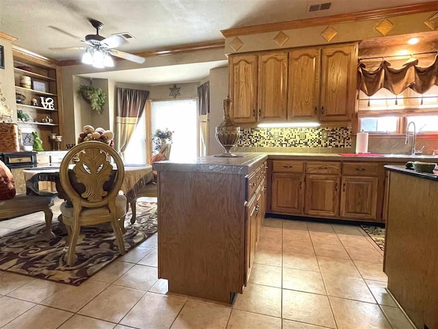 kitchen featuring ceiling fan, tasteful backsplash, light tile floors, and a healthy amount of sunlight