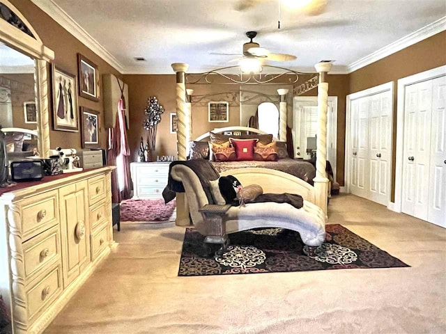 carpeted bedroom featuring ceiling fan, a textured ceiling, ornamental molding, and two closets