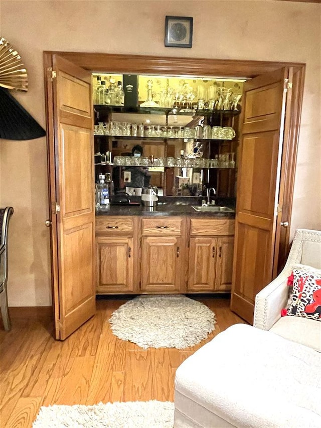 bar featuring light hardwood / wood-style floors and sink