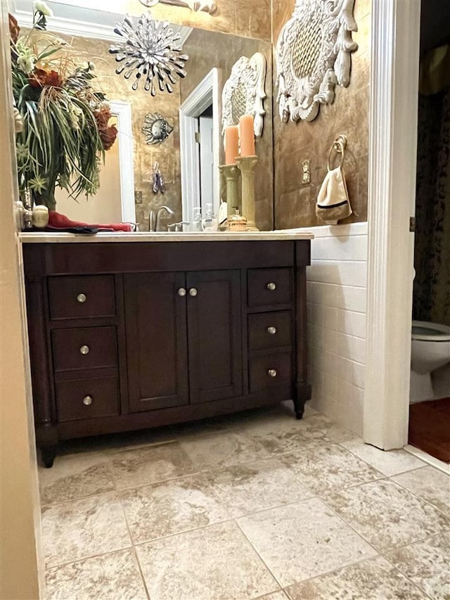 bathroom featuring toilet, tile floors, vanity, and tile walls