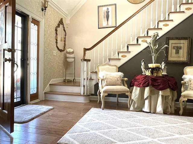 entryway with vaulted ceiling, hardwood / wood-style flooring, and ornamental molding